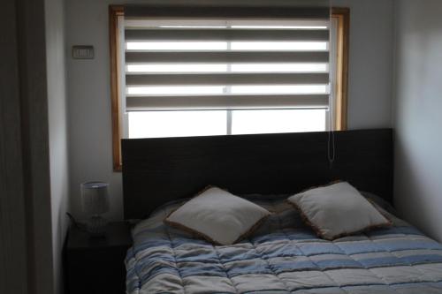 1 cama con 2 almohadas frente a una ventana en Maravilloso departamento en el sur de Chile, en La Unión