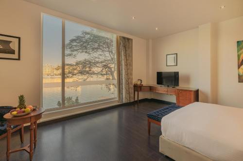 a bedroom with a large window with a bed and a desk at Riverside Hotel in Cairo