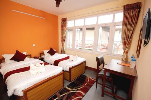 a hotel room with two beds and a desk and a window at hotel Backpackers inn in Kathmandu