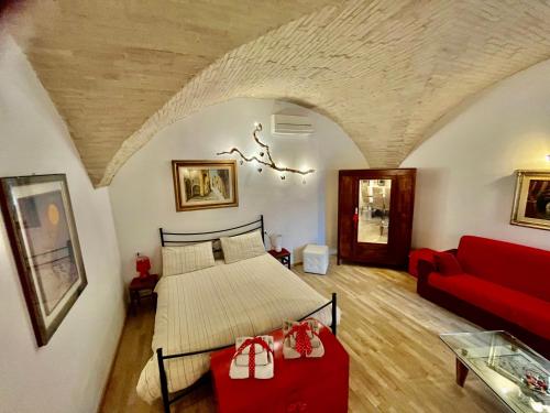 a bedroom with a bed and a red couch at Spello Vacanze Dante's House piano terra in Spello