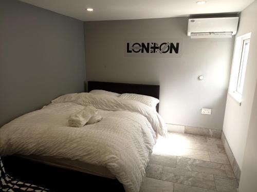 a bed in a bedroom with a sign on the wall at Luxurious En-suite Soft Water Air Conditioning TV RIPPLE in London