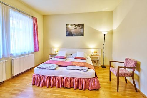 a bedroom with a large bed and a chair at Penzion Lípa in Krásná Lípa