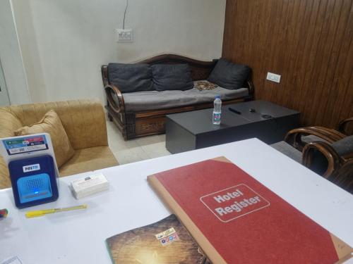 a living room with a couch and a table with a book at Hotel Galaxy Inn in Greater Noida