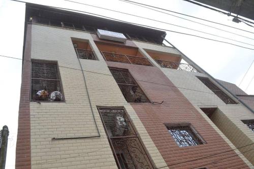 a tall brick building with two people looking out of their windows at HOTEL KEUTCHA in Douala