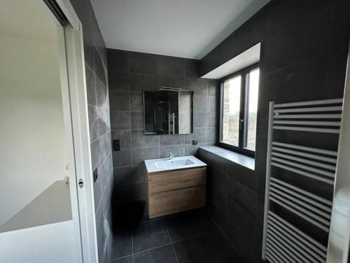 ein schwarzes Bad mit einem Waschbecken und einem Fenster in der Unterkunft une maison d'hôtes alliant charme et confort in Saint-Pierre-du-Val