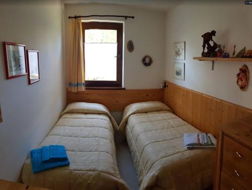 twee bedden in de hoek van een kamer met een raam bij Appartamento Pepe in Castello di Fiemme