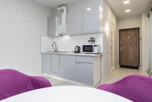 a white kitchen with purple chairs and a microwave at Люкс на Бориспільській ЖК Олімпік Парк, генератор на будинку in Kyiv