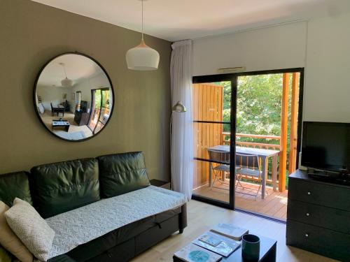 un salon avec un canapé et un miroir dans l'établissement Bel appartement cosy dans résidence avec piscine 5 minutes plage, à Messanges