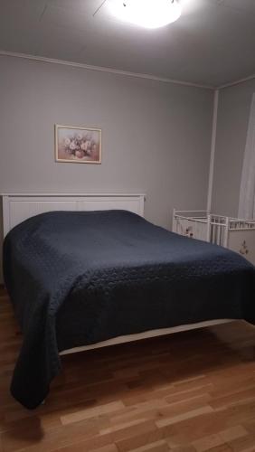 a bed in a bedroom with a black blanket at Paritalokolmio joen rannalla in Haapavesi