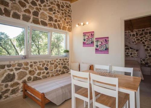 una sala da pranzo con tavolo e parete in pietra di Bungalow nefeli ad Agios Gordios