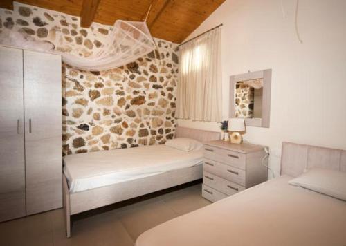 a bedroom with two beds and a stone wall at Bungalow nefeli in Agios Gordios