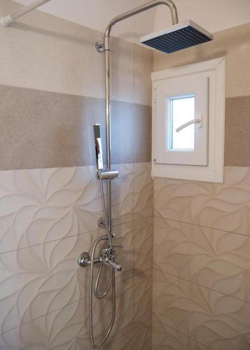 a shower stall in a bathroom with a window at Bungalow nefeli in Agios Gordios