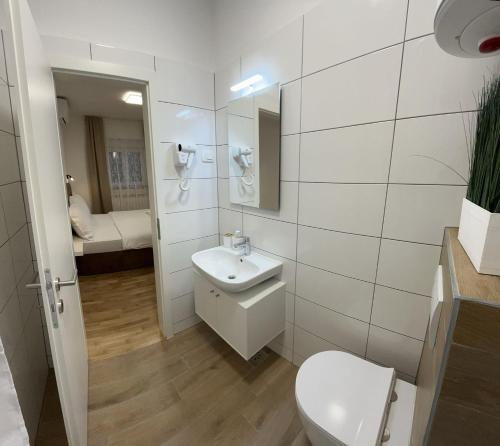 a white bathroom with a toilet and a sink at Apartmani Milat in Sveti Filip i Jakov
