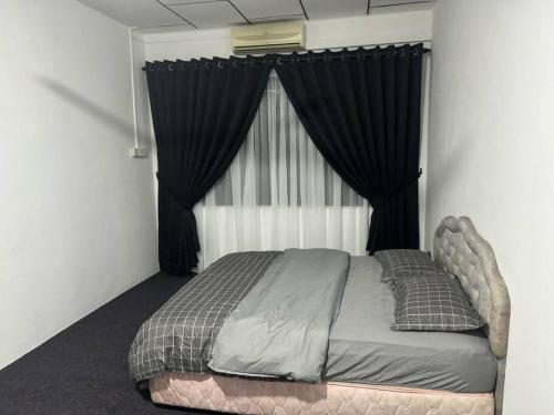 een bed in een slaapkamer met zwarte gordijnen bij Erma Homestay Kota Bharu in Kota Bharu