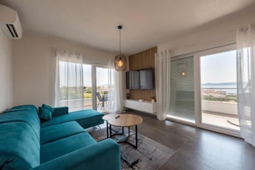 - un salon avec un canapé bleu et de grandes fenêtres dans l'établissement Apartment Karlo, à Trogir