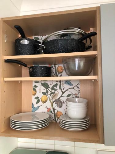 a cupboard with plates and pots and pans at Seaside Flat With Sunny Garden. in Brighton & Hove