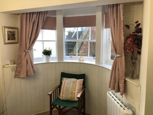 una silla en una habitación con ventana en Seaside Flat With Sunny Garden., en Brighton & Hove