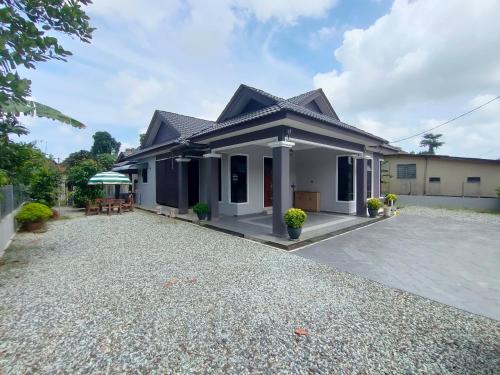a house with a gravel driveway in front of it at Zahani Homestay in Kuala Terengganu