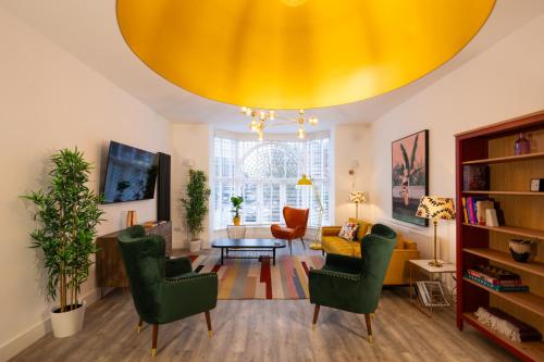 a living room with green chairs and a yellow ceiling at Lord Street Lofts in Southport