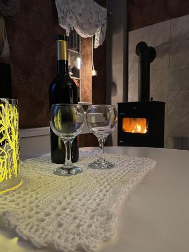 two wine glasses sitting on a table with a bottle of wine at Liebevoll renoviertes Ferienhaus im schwedischen Lappland Västerbotten in Björksele