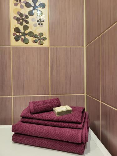 three purple towels sitting on a table in a bathroom at Iļģuciema Apartment in Rīga