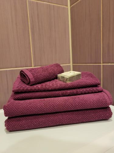 a pile of purple towels sitting on top of a sink at Iļģuciema Apartment in Rīga