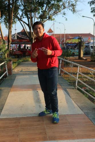 un hombre con un suéter rojo de pie en una acera en Rumah Pondok Kelapa 55m Dengan 2 Kamar Tidur en Yakarta