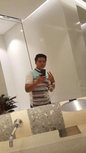 a man taking a picture of himself in a bathroom mirror at Rumah Pondok Kelapa 55m Dengan 2 Kamar Tidur in Jakarta