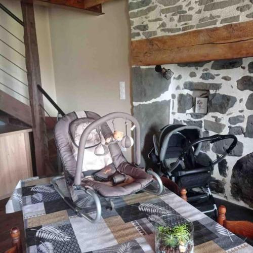 a room with a chair and a stroller next to a stone wall at Maison entière située à proximité du centre thermal de Chaudes-Aigues in Espinasse