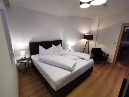 a bedroom with a bed with white sheets and a chair at Bella Vista Apartments in Nauders