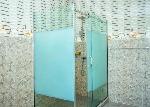 a shower with a glass door in a bathroom at Cis service apartment in Ketti