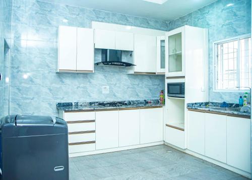 a kitchen with white cabinets and a black refrigerator at Cis service apartment in Ketti