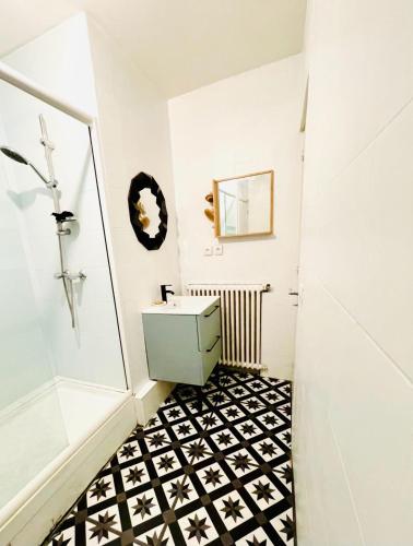 La salle de bains est pourvue d'un lavabo et de carrelage noir et blanc. dans l'établissement Bel appartement Stade de France piscine olympique, à Saint-Denis