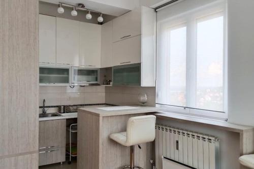 a kitchen with white cabinets and a white chair in it at Apartmani Beograd - Light Oasis in Belgrade
