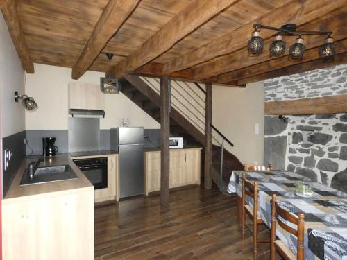 a kitchen with a table and a stone wall at Maison entière située à proximité du centre thermal de Chaudes-Aigues in Espinasse