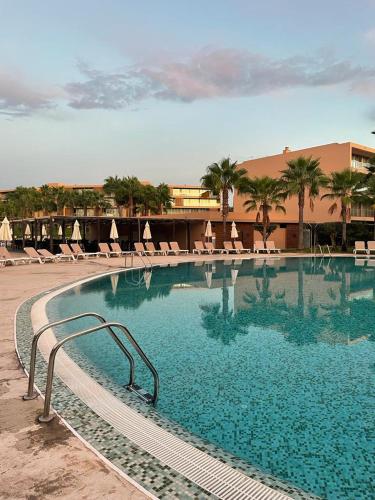 a large swimming pool with chairs and a building at Salgados - Vila das lagoas, Beach & Golf in Albufeira
