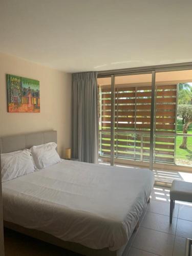 a bedroom with a white bed and a large window at Salgados - Vila das lagoas, Beach & Golf in Albufeira