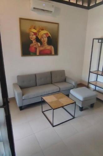 a living room with a couch and a table and a painting at Alamanda Bingin in Uluwatu