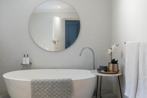 uma casa de banho com uma banheira branca e um espelho redondo em Eikehoff 25 em Stellenbosch