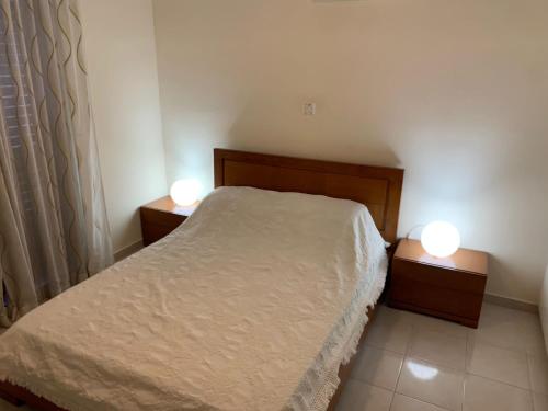 a bedroom with a bed and two lights on two tables at Exceptional townhouse in Paphos City