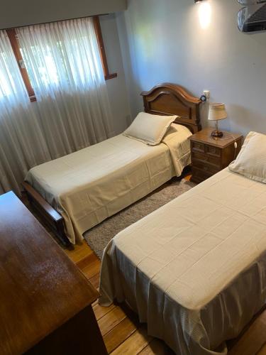 a bedroom with two beds and a table with a lamp at Santa Cruz 5761 in Mar del Plata