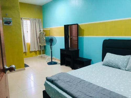 a bedroom with a bed and a blue and yellow wall at SOFEA HOMESTAY Islam sahaja in Seremban