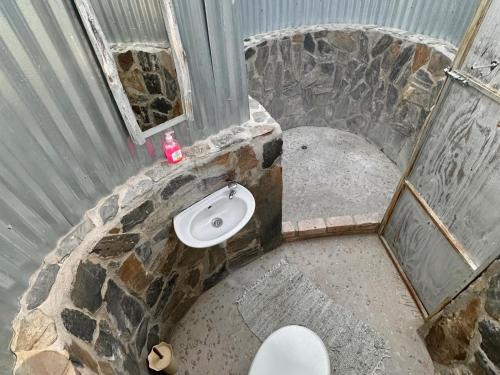 a stone bathroom with a toilet and a window at Daureb Isib Campsite and B&B in Uis