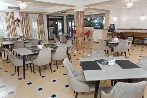 um restaurante com mesas e cadeiras num quarto em Pensiunea Noblesse em Baile Felix