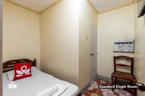 - une chambre avec un lit doté d'un oreiller rouge et d'une chaise dans l'établissement COFFEESWINGS LODGING HOUSE, à Vigan