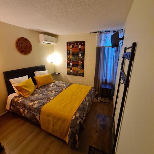a bedroom with a bed with yellow sheets and a window at Hôtel L'Etoile Aéroport - A61 in Carcassonne