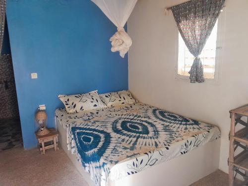 a bedroom with a bed with a blue wall at Campement Baobab in Poponguine