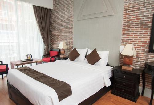 a bedroom with a large bed and a brick wall at Vacation Boutique Hotel in Phnom Penh
