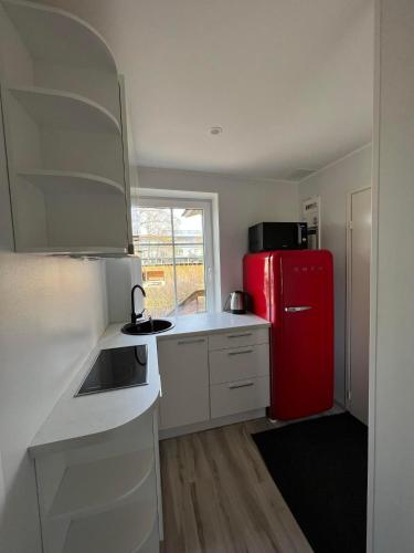タリンにあるSmall studio apartmentの赤い冷蔵庫と白いキャビネットのあるキッチン