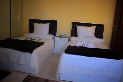a bedroom with two beds with white sheets at Energy Of Pyramid Hotel in Cairo